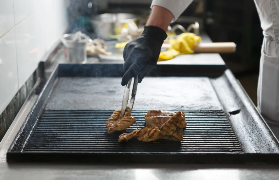 BBQ Gloves used for flipping chicken on a grill in a kitchen setting.